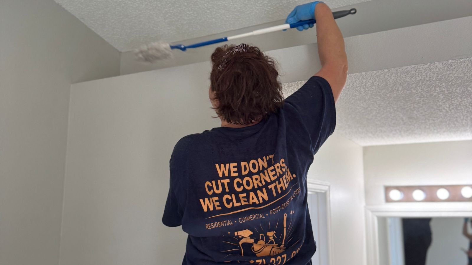 Dust Rush Cleaning team member dusting a high ledge with an extension duster.